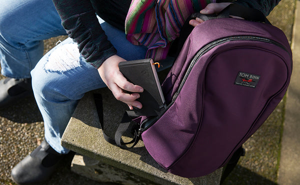 A person placing a pocket notebook in the small side pocket of the Luminary 15.